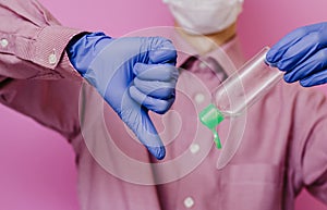 A guy in a medical glove holds an empty sanitizer. Thumb down. Pink background.