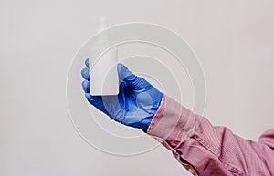 A guy in a medical glove holds a white bottle. White background