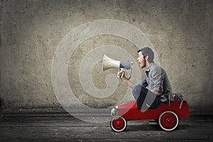 Guy with a megaphone in a toy car