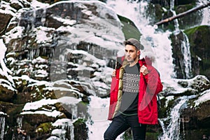 Guy model posing near the waterfall in winter mountains