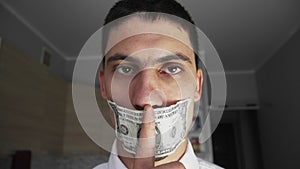 Guy with mouth sealed with dollar shows quieter. Puts her finger to her mouth. The theme of bribery and corruption.