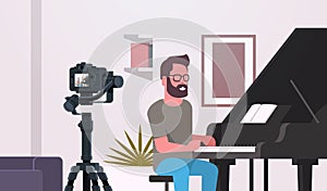 Guy musical blogger recording video on camera man playing classical piano music blog concept modern apartment interior