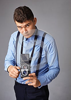 Guy with the old camera at the studio. Guy shoots on an old vintage film camera with two lenses.