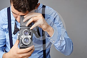 Guy with the old camera at the studio. Guy shoots on an old vintage film camera with two lenses.