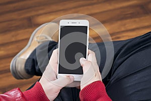 Guy operating touchphone while sitting in a wooden floor room