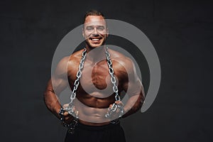 Guy with perfect body posing with chains in studio
