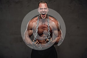 Guy with perfect body posing with chains in studio