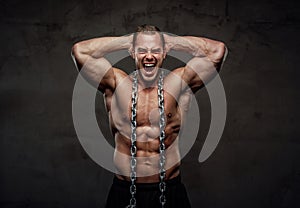 Guy with perfect body posing with chains in studio