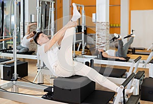 Guy performing exercises on Pilates reformer with sitting box photo