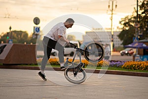 The guy performs a stunt on BMX, standing on the rear wheel