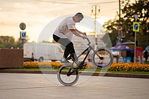 The guy performs a stunt on BMX, standing on the rear wheel
