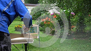 Guy performs work in yard as a hobby. Uses grinding tools, dust mask and glasses