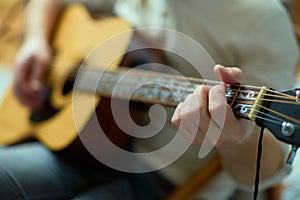 Guy play acoustic guitar, fingers on fingerboard, close-up. Musician perform classic music. Musical lesson, rehearsal