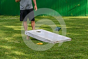 Guy playing bags game in backyard on sunny day