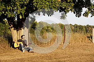 Guy Playing Guitar at Sunset under Maple Tree