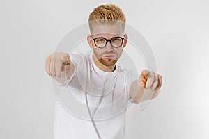 Guy pointing on you by fingers isolated on white background. Young stylish redheaded man, red beard and glasses. White t shirt