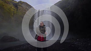 A guy poses in front of the backdrop of the huge Skogafoss waterfall