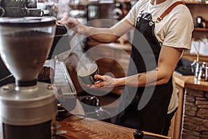 A guy is pouring hot water in the cup in the coffee bar