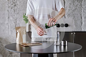 Guy pours tea leaves in infuser for brewing at home kitchen