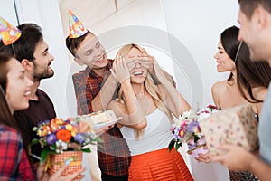 The guy prepared a surprise for the girl`s birthday. He closed her eyes by hands. The guy smiles and leads the girl to a