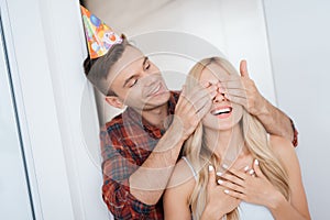 The guy prepared a surprise for the girl`s birthday. He closed her eyes by hands. The guy smiles and leads the girl to a