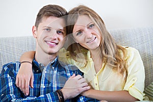 Guy and pretty girl cuddling on sofa indoors