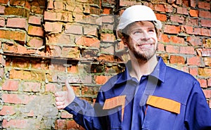Guy protective helmet bearded handsome builder. Builder helmet construction site brick wall background. Man take break