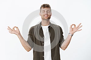 Guy reaching nirvana feeling happy and relaxed released from stress meditating with closed eyes, broad satisfied smile photo