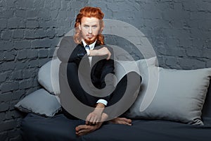 Guy with red hair and beard, sitting on the sofa.