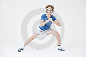 Guy in retro sport suit doing stretching exercises. White background