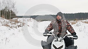 The guy is riding an ATV on a snow-covered road in winter