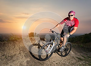 Guy riding on the mountain bicycle against evening sky