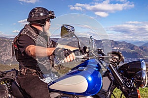 Guy riding a retro cruiser motorcycle on mountain road in South tyrol enjoying the beautiful view