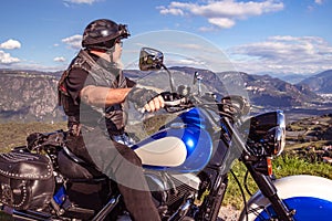 Guy riding a retro cruiser motorcycle on mountain road in South tyrol enjoying the beautiful view