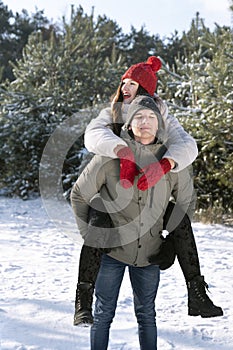 Guy rolls girl on his back. Loving young couple is having fun in winter outdoors