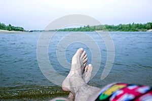 Guy`s feet, by the river, enjoy the beach holiday, high and relaxation