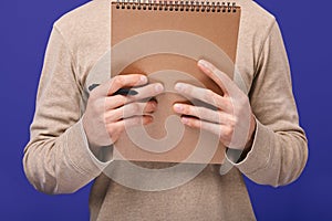 The guy`s hands holding ballpoint pen and brown draft notebook photo