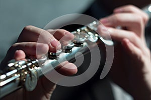 Guy`s hands on a wind musical instrument. Playing the flute. Shallow depth of field. Music and sound. Modeling light.