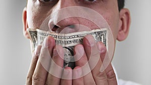 The guy's mouth sealed with dollar bill. Panic. Can't speak. The theme of bribery and corruption. On a white background. Close up