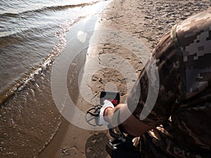 Guy on a sandy coast looking for treasure with a metal detector on a sunny summer day