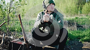 The guy sat down to rest on a log in a vacant lot. On the guy`s headphones