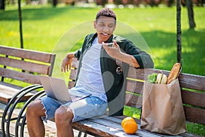 Guy saying message on smartphone sitting on bench