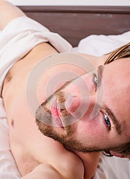 Guy macho lay white bedclothes. Playful mood concept. Man unshaven handsome torso relaxing bed. Pleasant relax