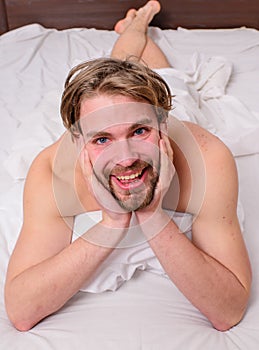 Guy macho lay white bedclothes. Pleasant relax concept. Playful mood concept. Man unshaven handsome happy smiling