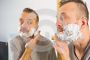 Guy shaving his beard in bathroom