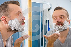 Guy shaving his beard in bathroom