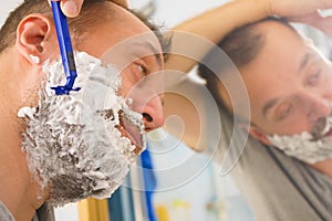 Guy shaving his beard in bathroom