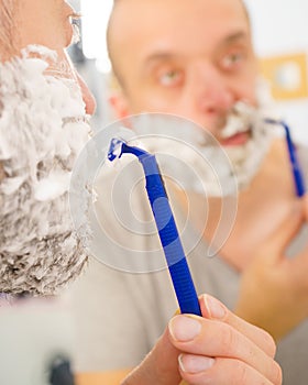 Guy shaving his beard in bathroom