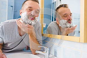 Guy shaving his beard in bathroom