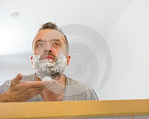 Guy shaving his beard in bathroom